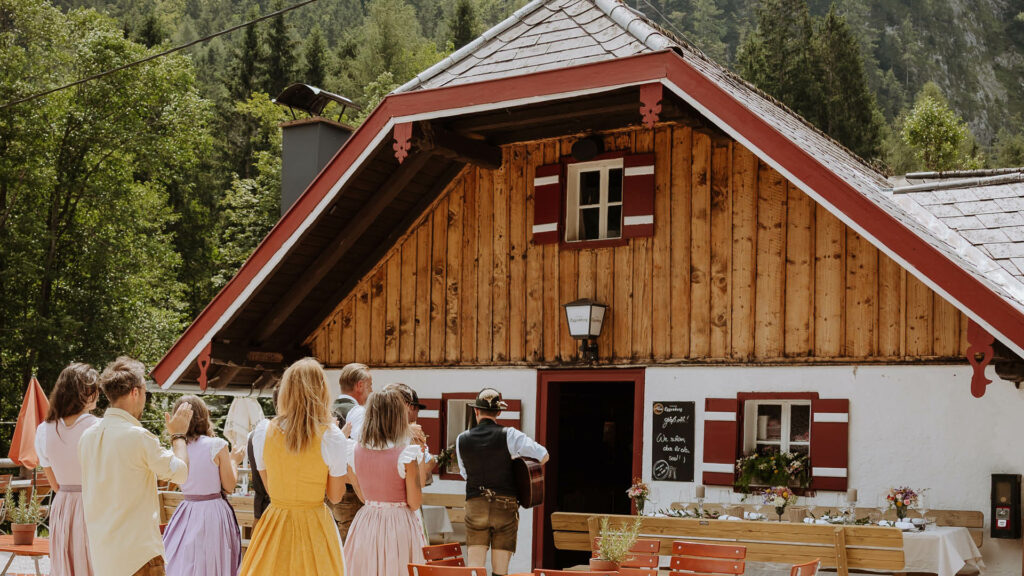 Eine Gruppe Feiernder spaziert in Richtung Eventlocation Almstadl am Schwarzensee. Einer urigen Hütte in St. Wolfgang.